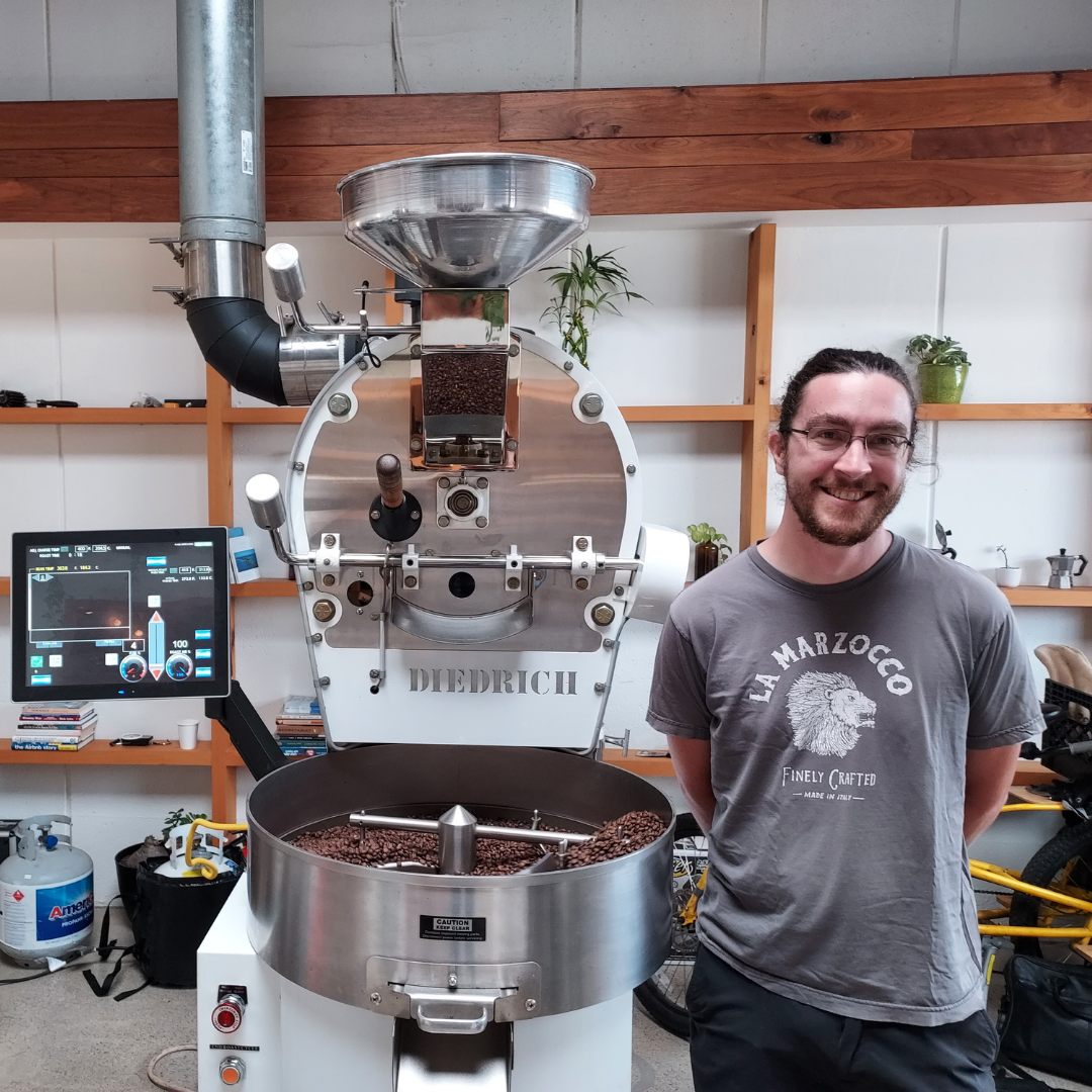 Chris O'Brien of Coffee Cycle Roasting standing next to a whit and silver Diederich Coffee Roasting Machine