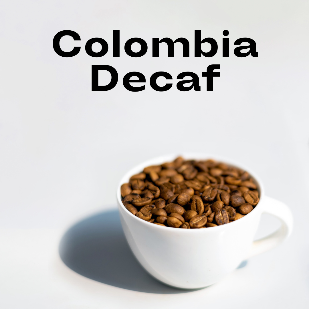 a white coffee cup filled with dry, roasted, coffee beans and the tag Colombia Decaf above it on a white background.